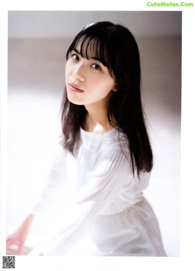 A woman in a white dress is posing for a picture.