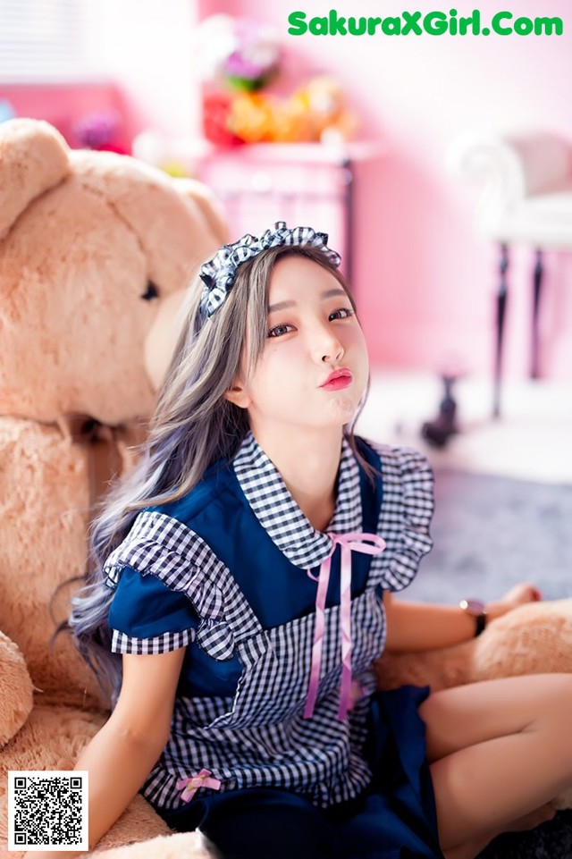 A woman sitting on the floor next to a teddy bear.