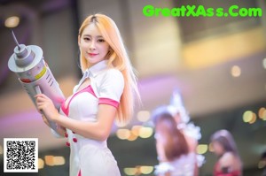 A woman in a white and pink outfit holding a gun.