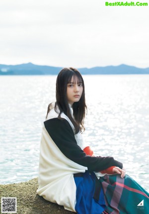 A woman in a white shirt and colorful skirt standing on a road.