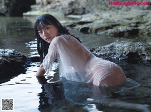 A woman in a white dress sitting in the water.