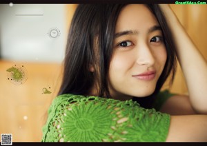 A woman with long black hair wearing a green sweater.