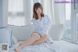 a woman sitting on top of a bed in a white shirt