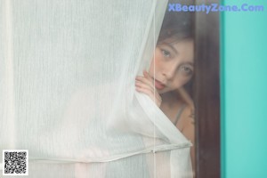 A woman in a gray tank top and white shorts posing on a balcony.