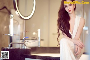 A woman in a white dress standing in a bathroom.