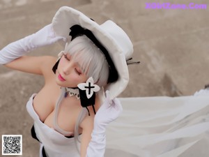 A woman in a white dress and hat posing for a picture.