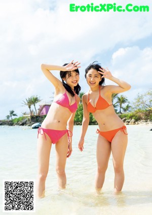 A couple of young women standing next to each other near a pool.