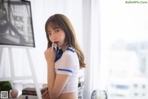 A woman in a white shirt and blue shorts standing in a doorway.