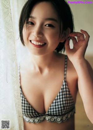 A woman in a blue bikini standing by a window.