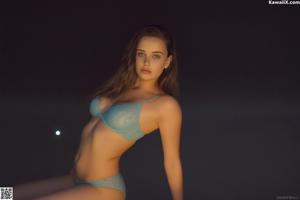 A woman in a black bra and panties posing by a pool.