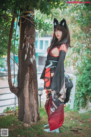 A woman in a black and red kimono sitting on the ground.