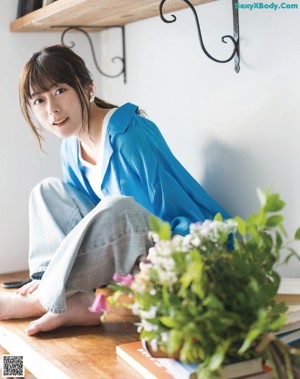 A woman sitting on a wooden table reading a book.