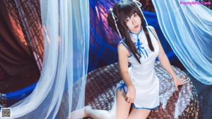 A woman in a white and blue outfit sitting on a bed.
