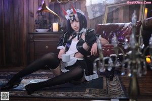 A woman dressed as a maid sitting on a stool.
