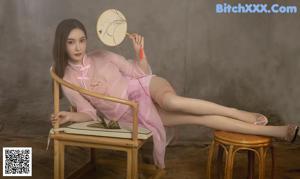A woman in a pink dress sitting on a chair.