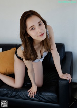 A woman laying on top of a black couch.