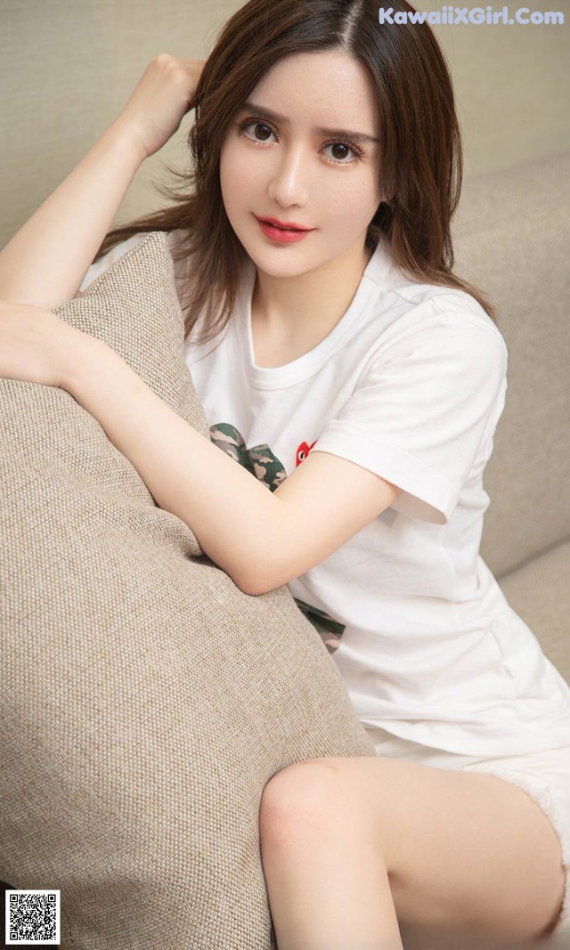 a woman sitting on top of a couch next to a pillow