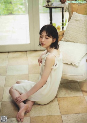 A woman sitting on a couch in front of a window.